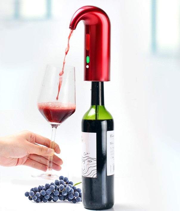 Electronic wine aerator in use, pouring wine into a glass from a bottle, red sleek design, placed on a table with grapes nearby.