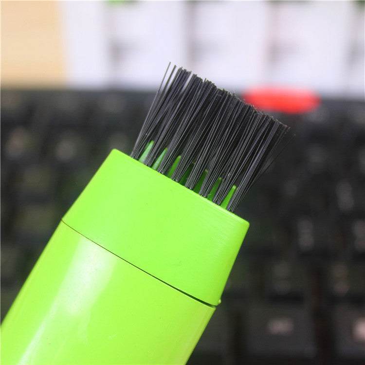 Close-up of mini computer keyboard cleaner brush with black bristles and green handle.