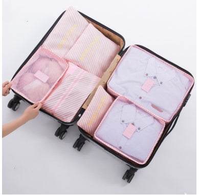 Open suitcase with pink durable waterproof nylon packing cubes organizing clothes.