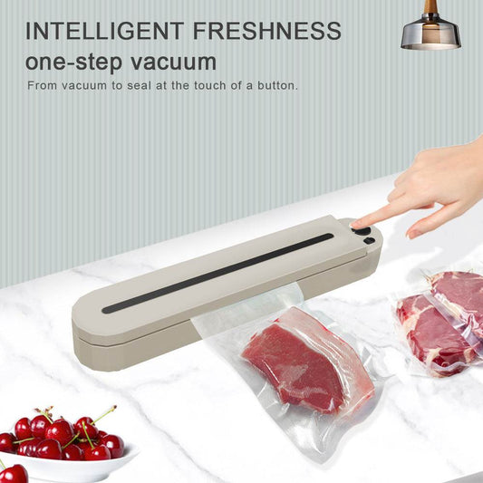 Mini vacuum sealing machine in use with sealed meat bags on a kitchen counter.