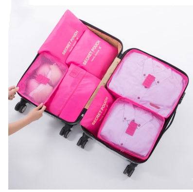 Pink waterproof nylon packing cubes in a suitcase, organizing clothes.