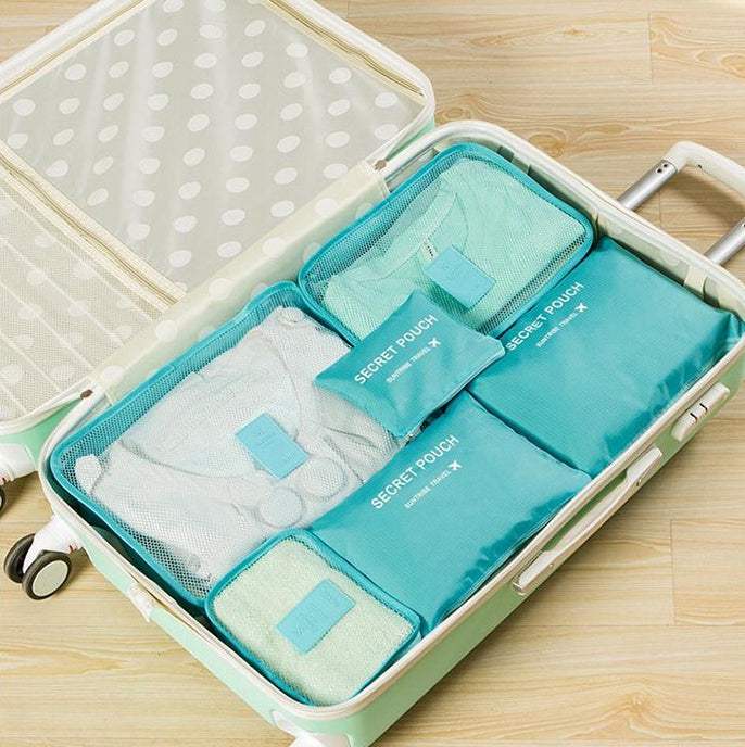 Travel organizer bag set in a suitcase with clothes neatly packed in blue nylon and mesh fabric cubes.