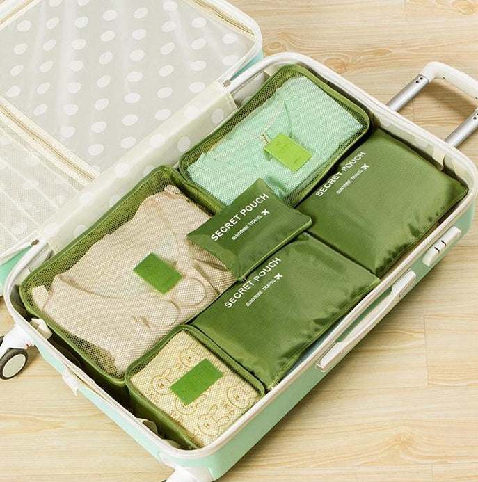 Luggage organized with green waterproof nylon packing cubes in a suitcase.